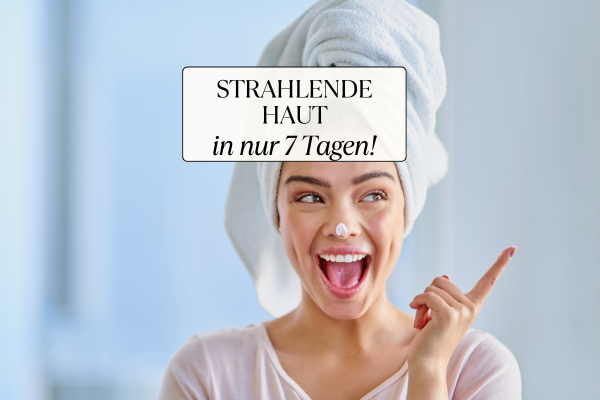 Lächelnde Frau mit Handtuchturban und Gesichtscreme zeigt auf den Text ‚Strahlende Haut in nur 7 Tagen!‘ – Hautpflegeroutine gegen Pickel und Unreinheiten
