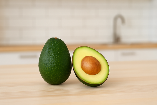 Ganze und halbierte Avocado auf einem hellen Holztisch in einer modernen Küche – Symbol für gesunde Ernährung und natürliche Hautpflege.
