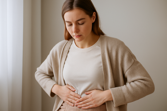 Frau in neutraler Umgebung mit sanften Farben hält ihre Hände auf dem Bauch als Symbol für die Verbindung zwischen Darm und Haut.