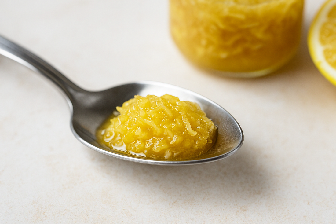 Nahaufnahme eines Löffels mit einer frischen Mischung aus geriebenem Ingwer, Honig und Zitrone auf hellem Hintergrund – natürliche Kur für Gesundheit, Immunsystem und reine Haut.