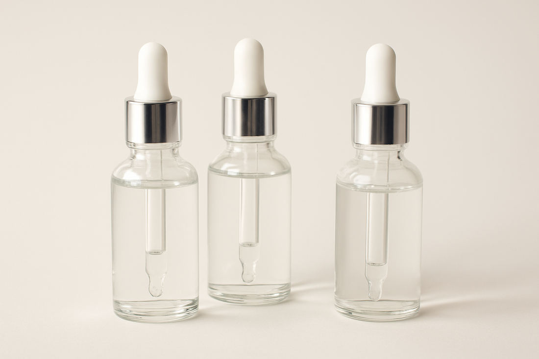 Mehrere Pipetten mit klarem Serum vor einem hellen, minimalistischen Hintergrund, ästhetisch angeordnet.