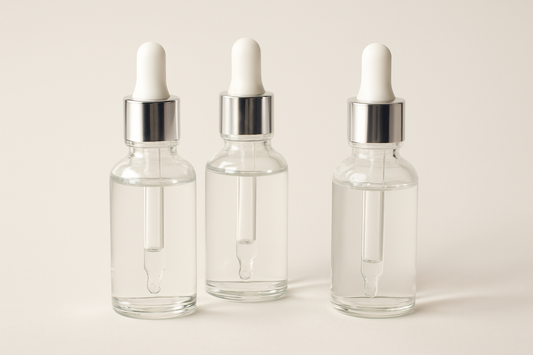 Mehrere Pipetten mit klarem Serum vor einem hellen, minimalistischen Hintergrund, ästhetisch angeordnet.